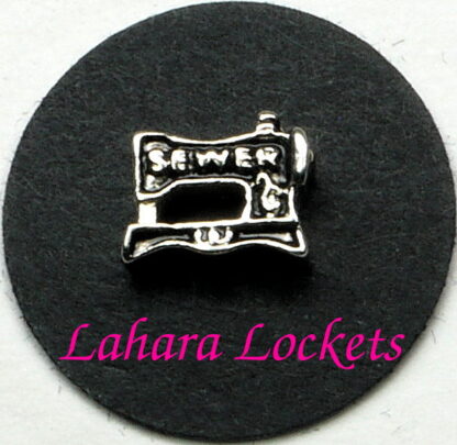 This floating charm is a black and silver, retro sewing machine that says sewer on it in silver.